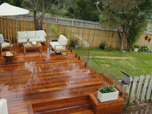 Back garden with timber decking showcasing glass fencing and lounge