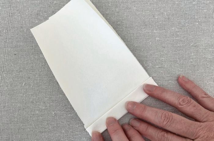 Hands fold piece of paper in half
