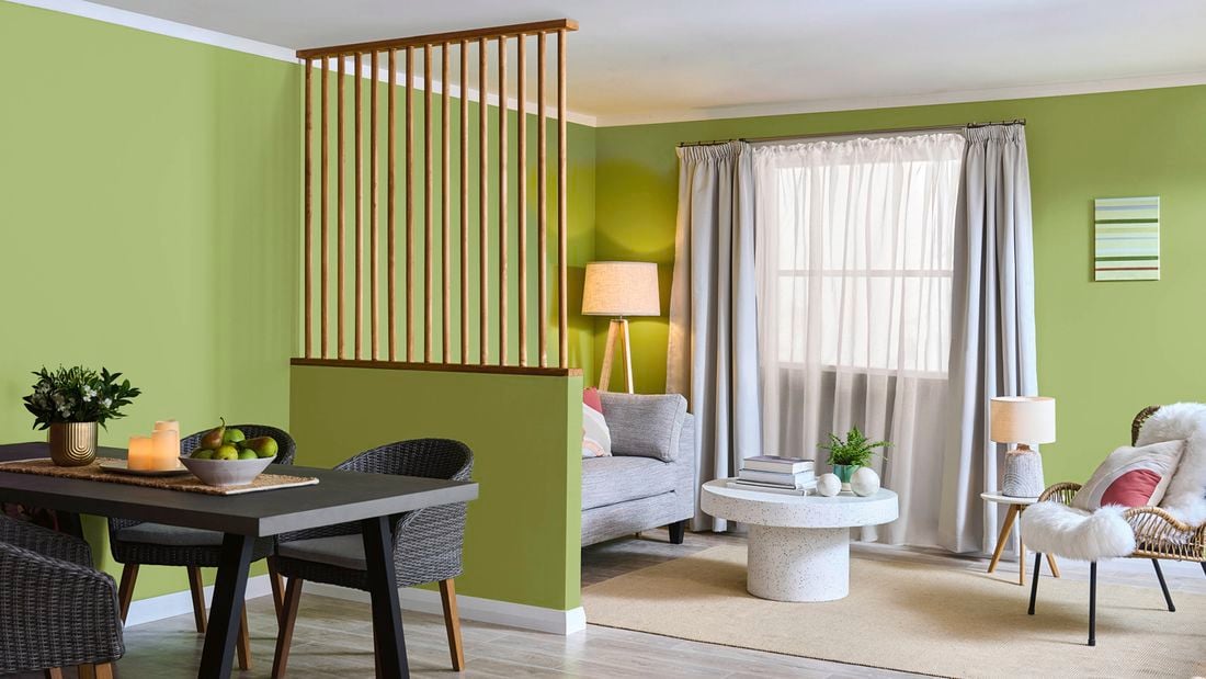 A dining table divided by a lime green wall with a loungeroom setting showing living flexible spaces