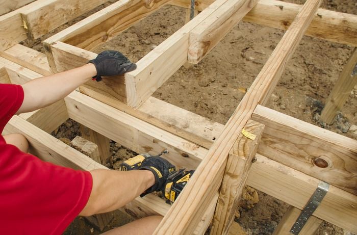 Bunnings Tem member wearing gloves and screwing timber together with  a drill