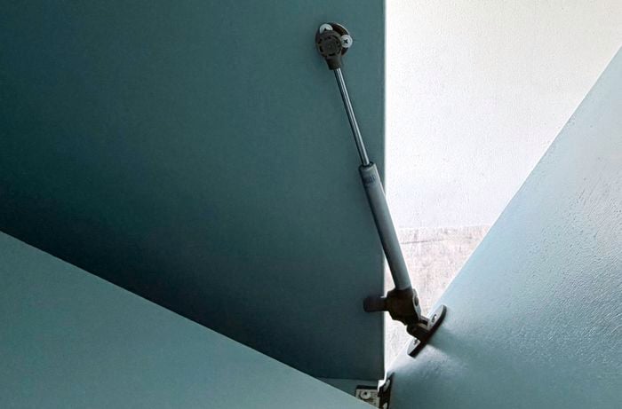 A gas strut installed on a cabinet door.