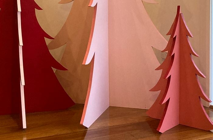 Three plywood Christmas trees painted pink and red.