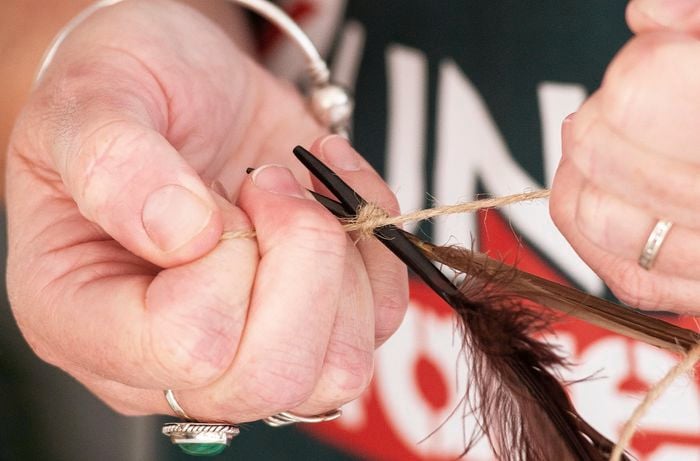 Tying a feather to the orange string.