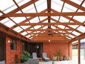 Roofing over an outdoor patio with deck chairs and a dining table area.