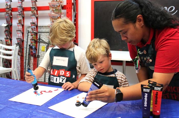 Bunnings team member and children painting.