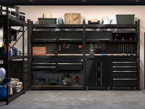 A garage space featuring Rack It storage solutions against the wall and on both sides, featuring shelves, pegboards and drawer units