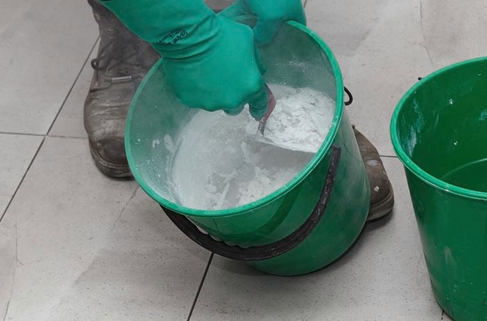 Grout being mixed in a bucket with a trowel