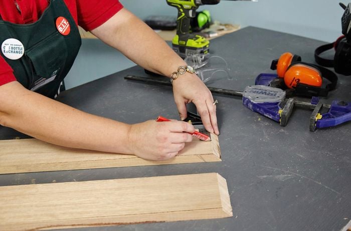 Person measuring and marking timber with pencil