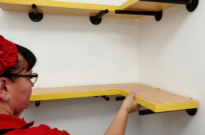 A completed shelf being placed on mounted wall pegs