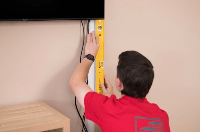 Holding an adhesive cable cover and a spirit level.