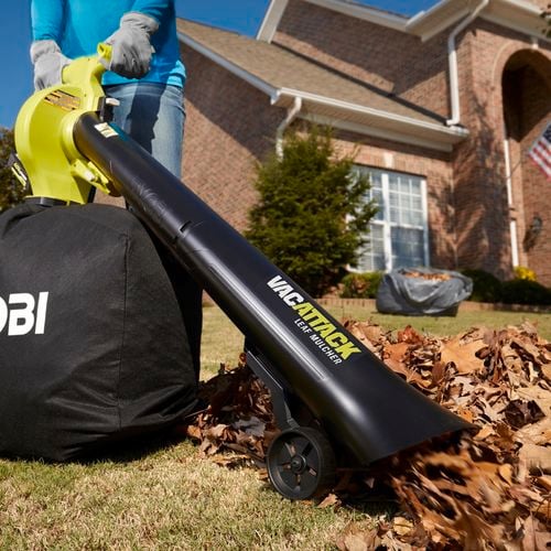 A person using a garden vacuum to clean the garden.