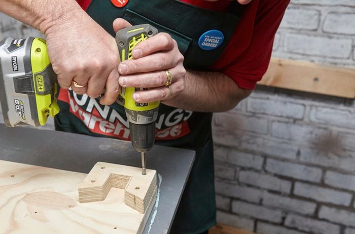 Person drilling holes into timber bracket.