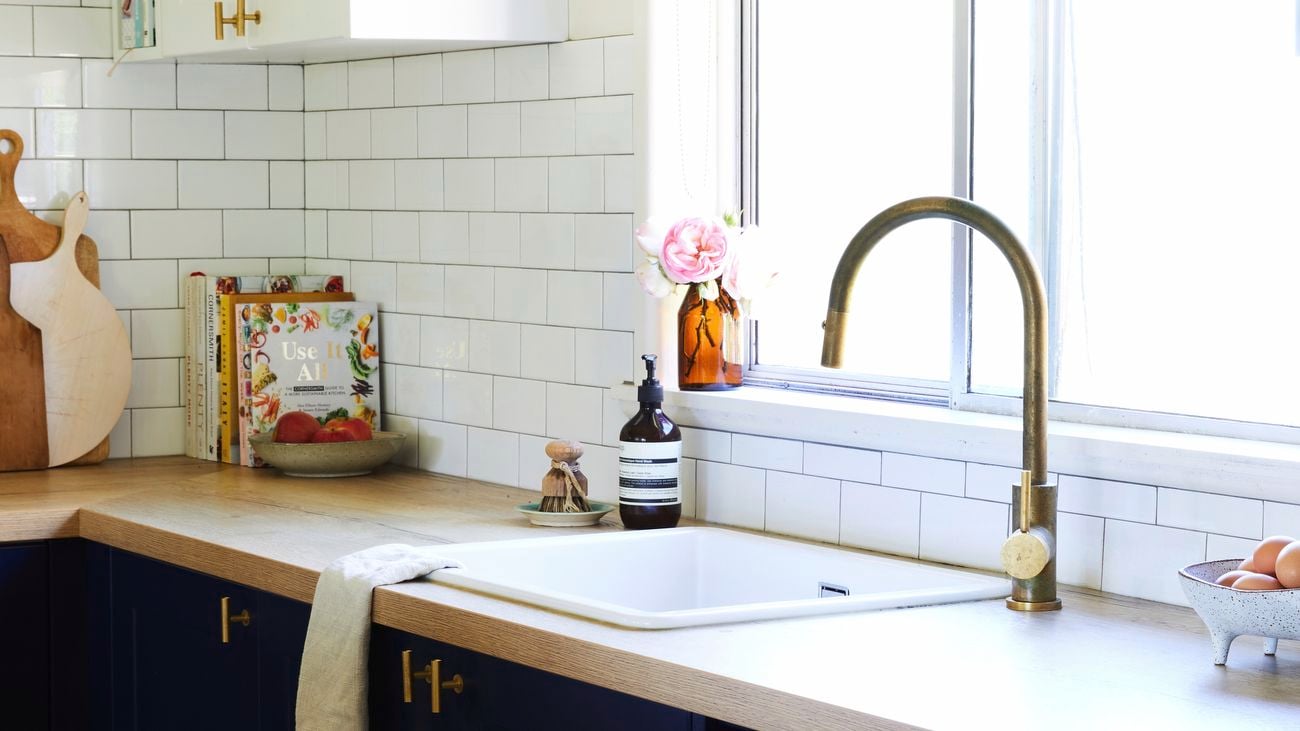 Kitchen sink with vase, books and overhead storage cabinet