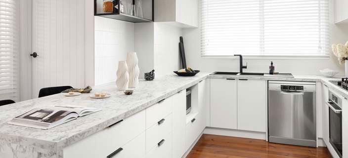 White kitchen with black accents and stone-look benchtops.