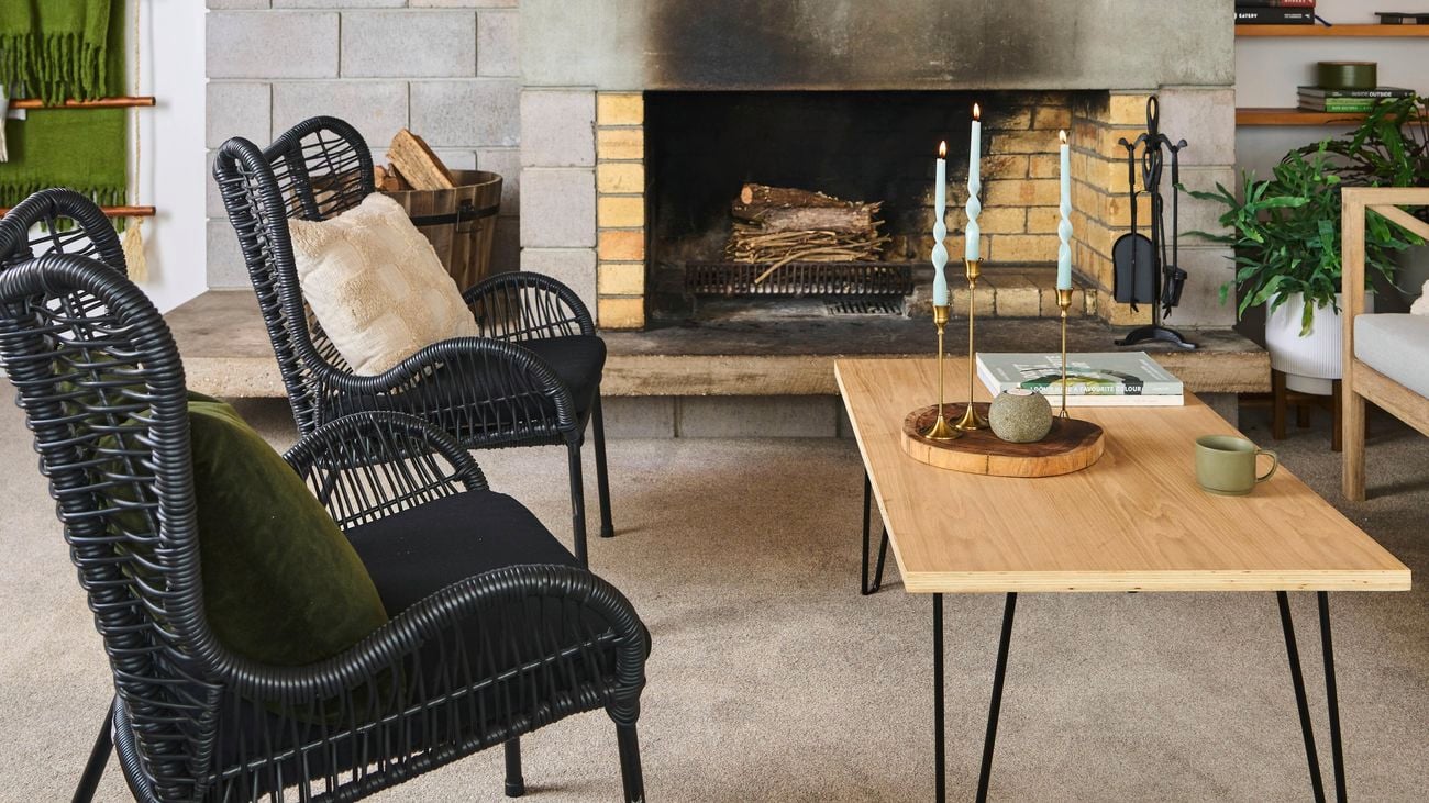 A cosy living room with an unlit fireplace, two armchairs and a coffee table