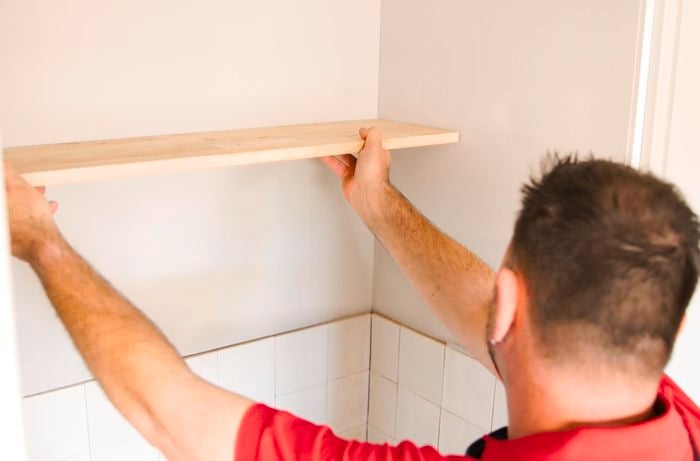 A person installing shelves.