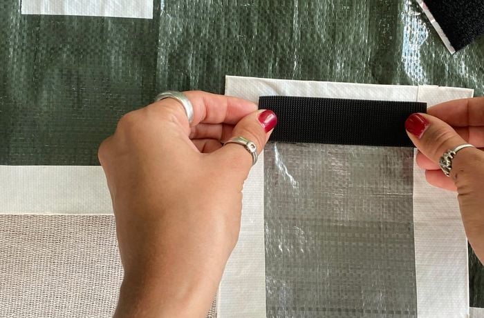 A pair of hands attaching a velcro strip to a tarp