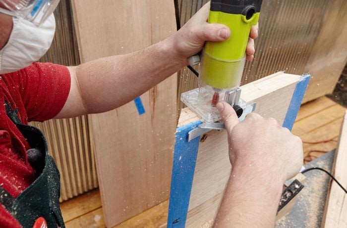 A person wearing safety glasses and mask routing the end of a piece of timber