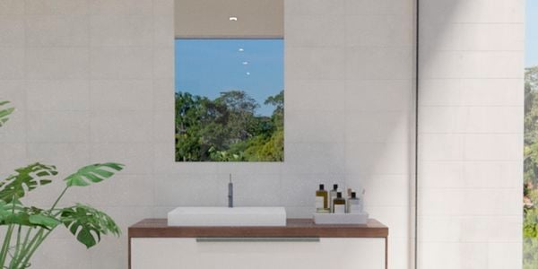 Bathroom with flat edged mirror along with wash basin, plant, caddy and white wall tiles.