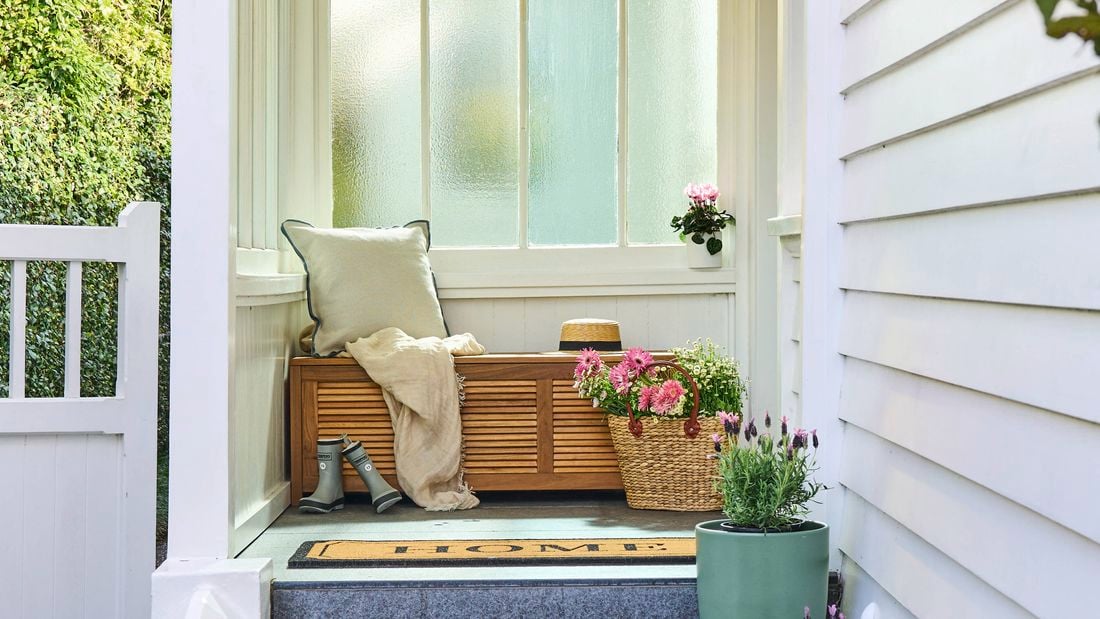 An entranceway featuring spring flowers and a timber daybed