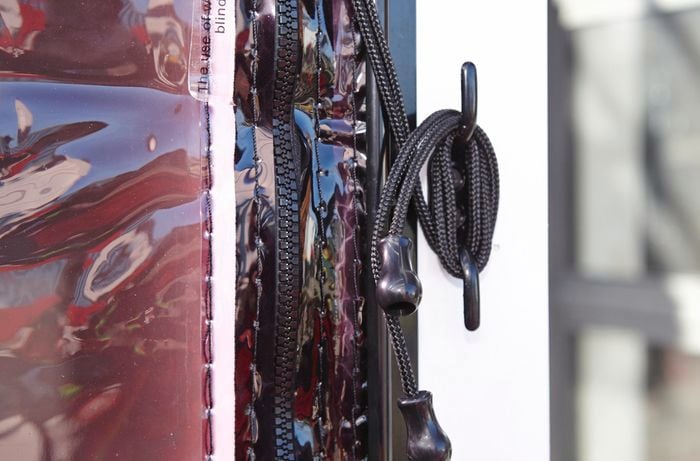 A close-up of a blind cord wrapped around a cleat on a post