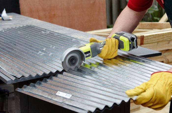 Person using handheld circular saw to cut through piece of metal.