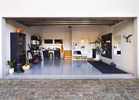 Wide shot of a garage makeover, featuring an epoxy floor, storage units and gym equipment