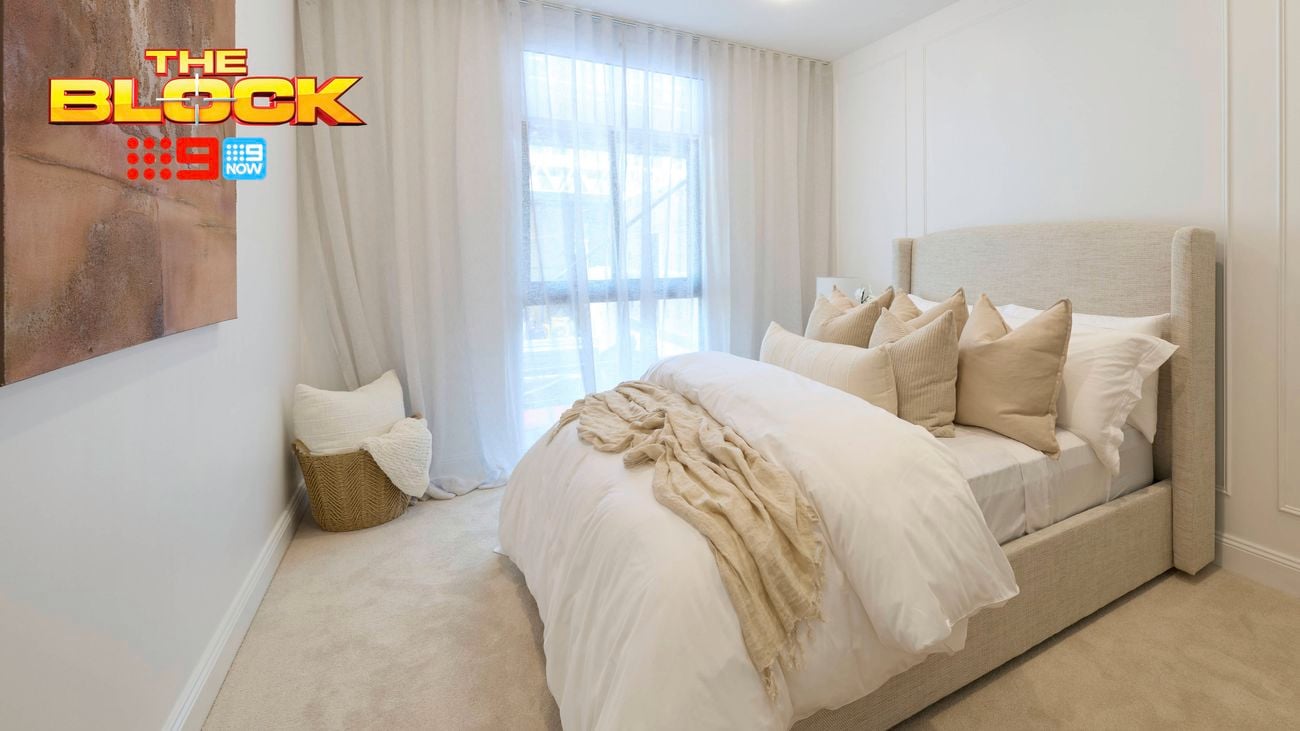 A furnished bedroom with a bed, basket with a cushion in it, painting on the wall and carpet on the floor.