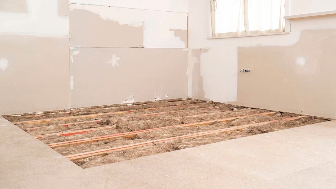 Insulation batts installed between floor joists.