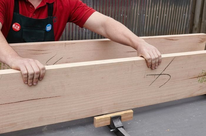A person checking two lengths of wide hardwood timber