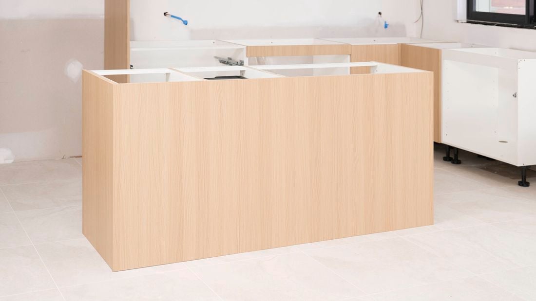 The image shows a nearly completed kitchen island bench cabinetry in a kitchen under construction.