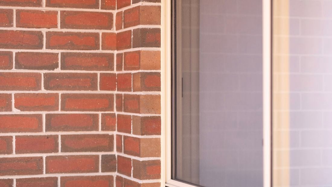 The image displays a brick wall with a half window.