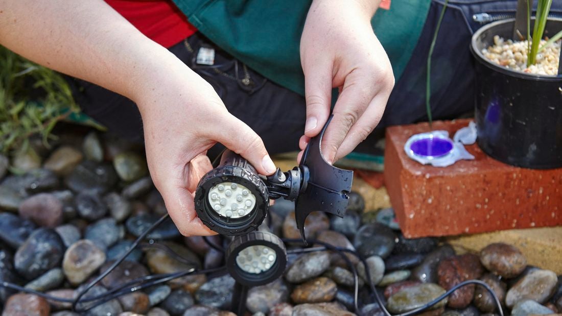 A person attaching a pond light to a weighted base