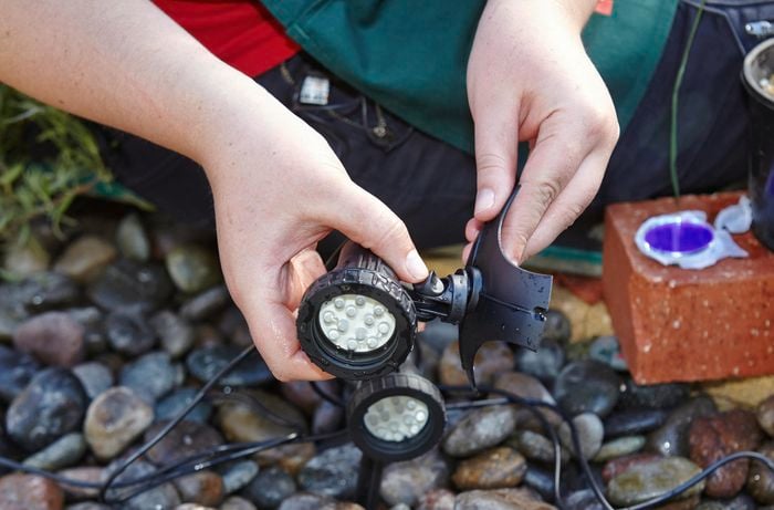 A person attaching a pond light to a weighted base