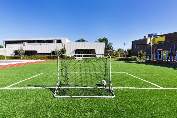 A soccer pitch surrounded by an athletics track with a soccer goal and ball
