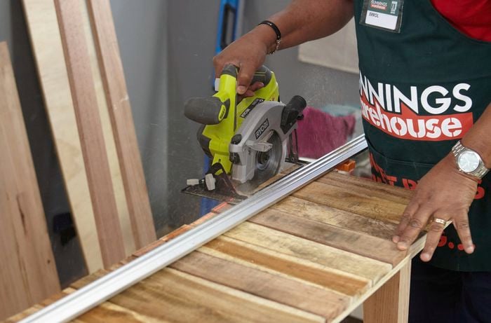 Person trimming edges from timber slats with a circular saw
