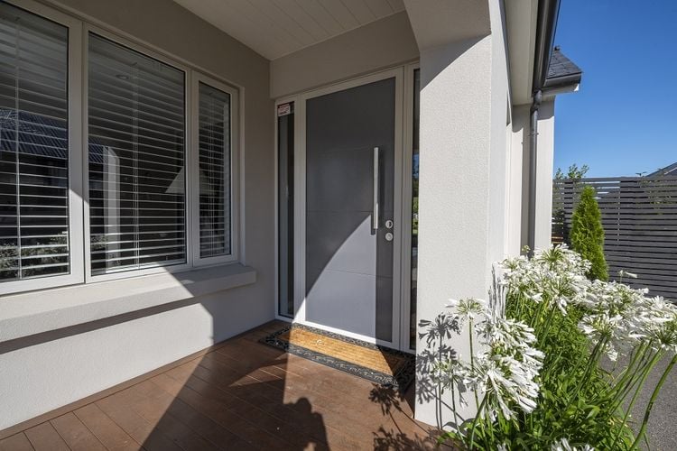 Exterior of a modern townhouse painted pale grey with a dark grey front door