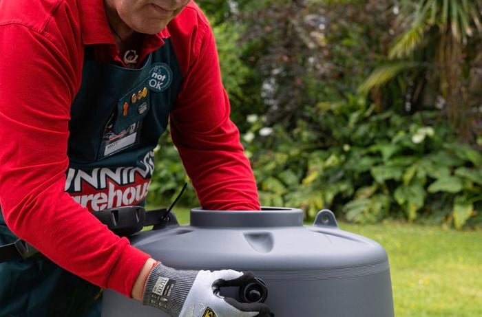 A Bunnings employee removes nut from rainwater tank.