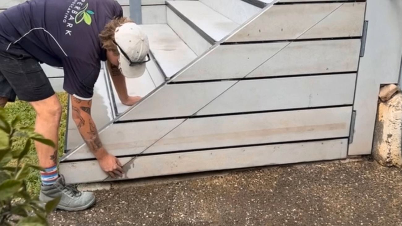 The back of a landscaper putting down light coloured HardieDeckTM boards to create a stairway for extra storage solutions.