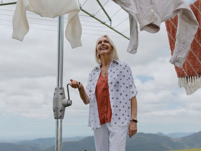 Woman winding up a Hills Heritage Hoist 6 Line Clothesline.