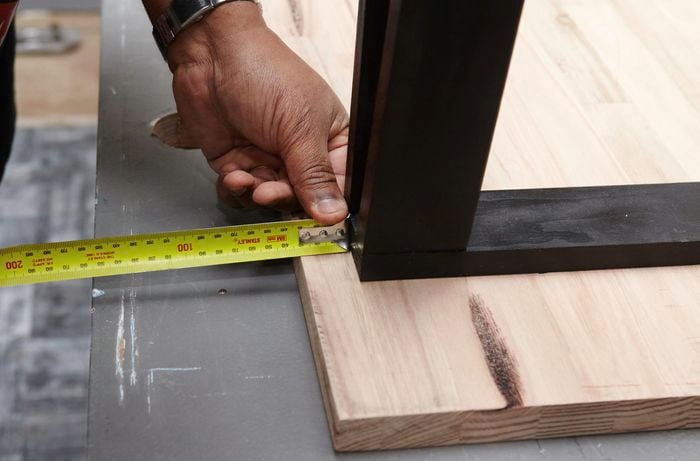 A person measuring distance from the edge of table top on an inverted table