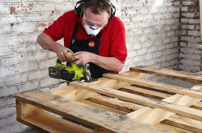 A Bunnings team member cutting into a wooden pallet