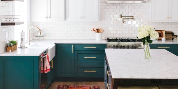 Kitchen with teal cabinets and white benchtops.
