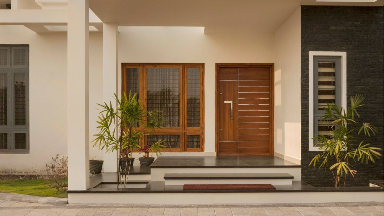 Wide shot of a wooden front door of a modern, cream-coloured house.