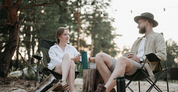 man and lady sitting on camp cars enjoying a drink