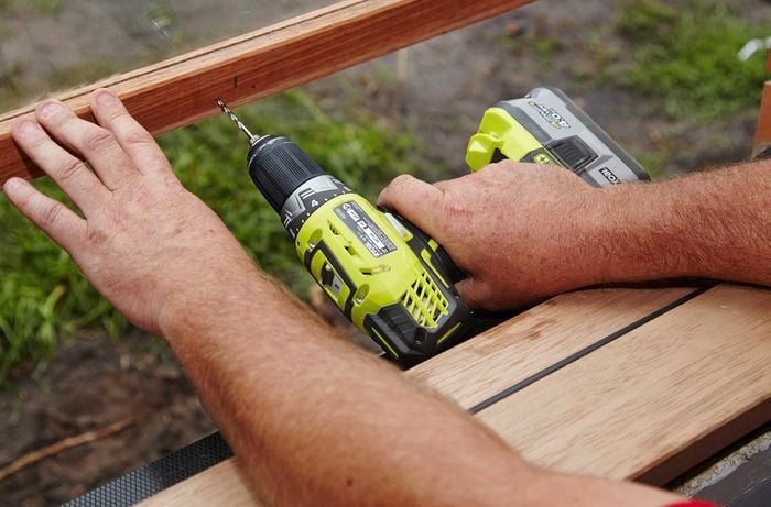 A drill being used to drill pilot holes in a window