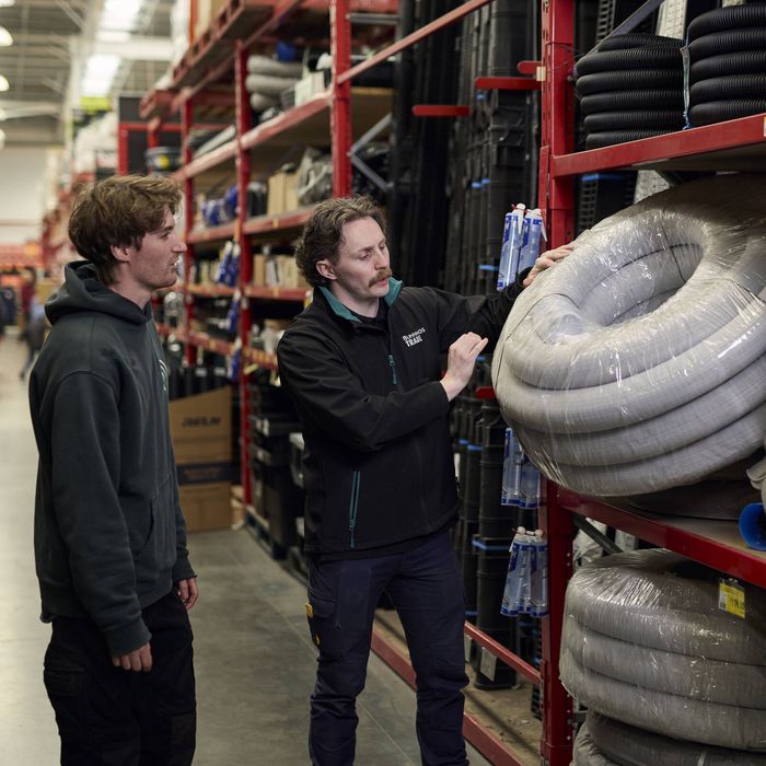 Bunnings team member assisting a customer with coiled hoses in a store aisle.
