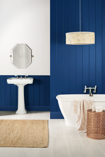 Retro wood panelled bathroom painted dark blue, with basin, mirror and freestanding bath