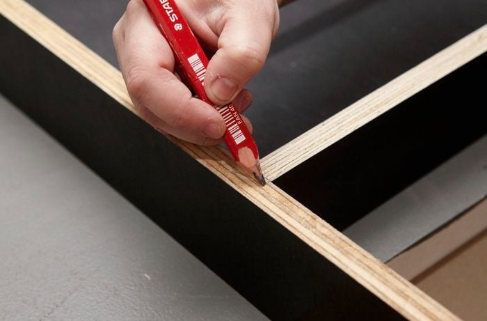 Person marking up form ply frame with pencil.