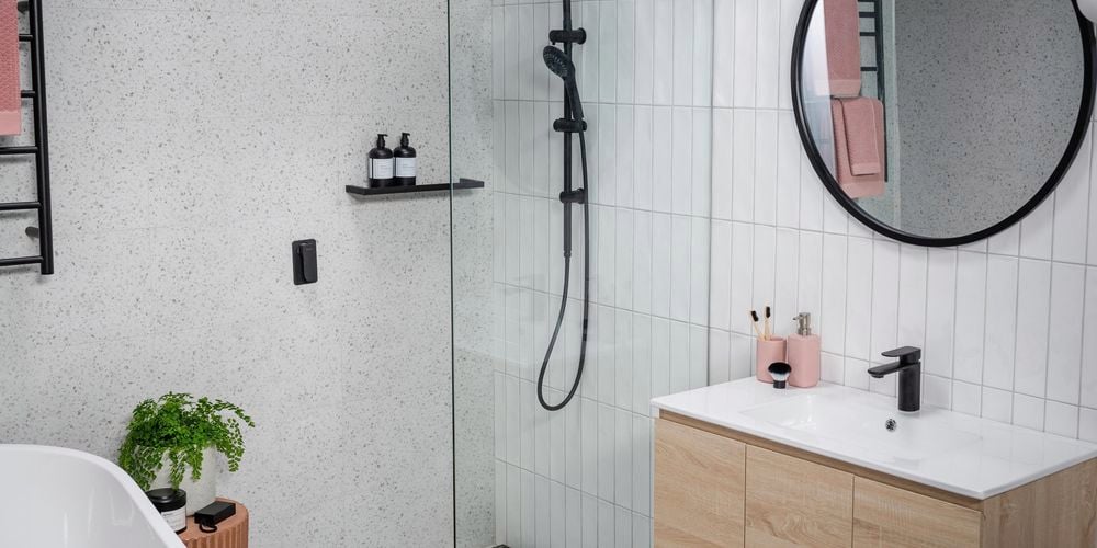 Bathroom with marble wall and white tiled walls with black colour fittings. 